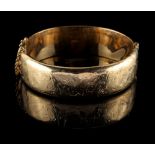 Property of a deceased estate - a 9ct gold hinged bangle, with engraved foliate decoration, with