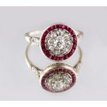 An unmarked white gold or platinum ruby & diamond circular cluster ring, with nine round cut