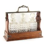 Property of a deceased estate - an early 20th century oak roll-top tantalus with three bottles or