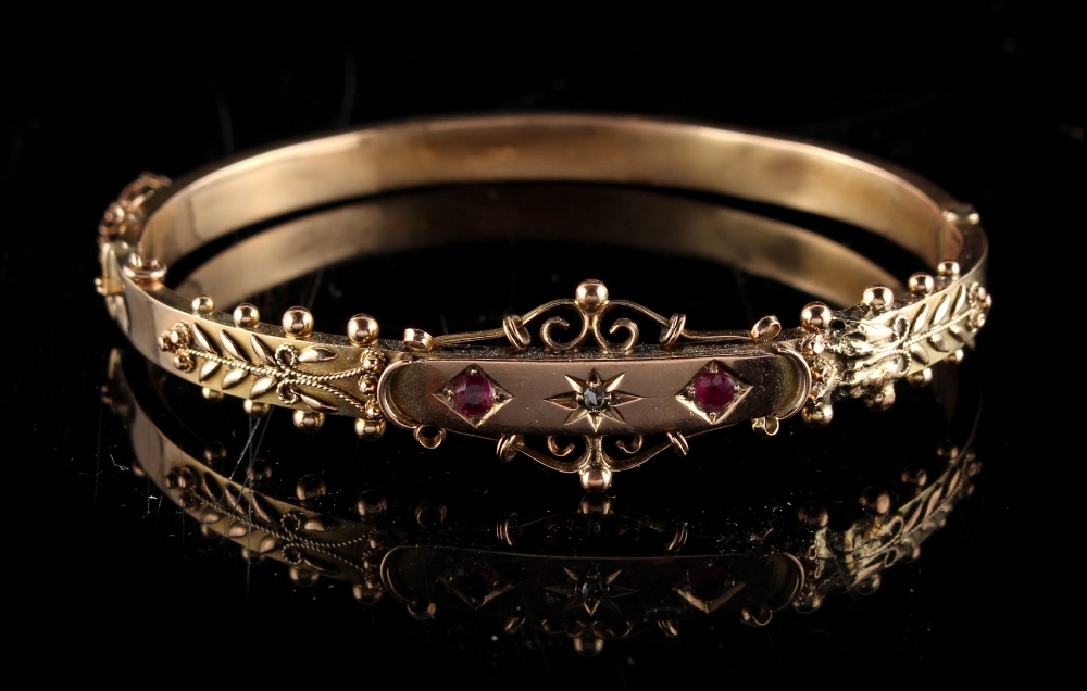 Property of a deceased estate - a 9ct gold hinged bangle set with two round cut rubies flanking a