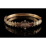 Property of a deceased estate - a 9ct gold hinged bangle set with two round cut rubies flanking a