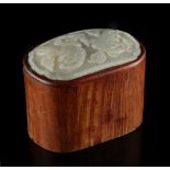 A 19th century Chinese hongmu oval box, the cover inset with a pale celadon jade panel carved in