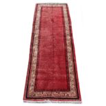 An Arak woollen hand-made carpet with red ground, 122 by 44ins. (310 by 110cms.).