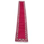 A Tabriz woollen hand-made runner with burgundy ground, 189 by 32ins. (480 by 80cms.).