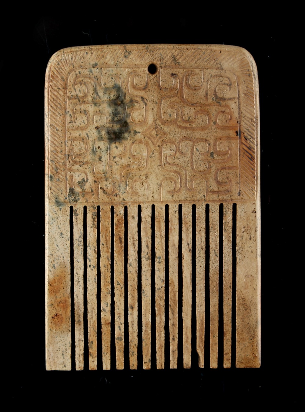 A Chinese archaistic jade comb, with carved panels, 3.15ins. (8cms.) long.