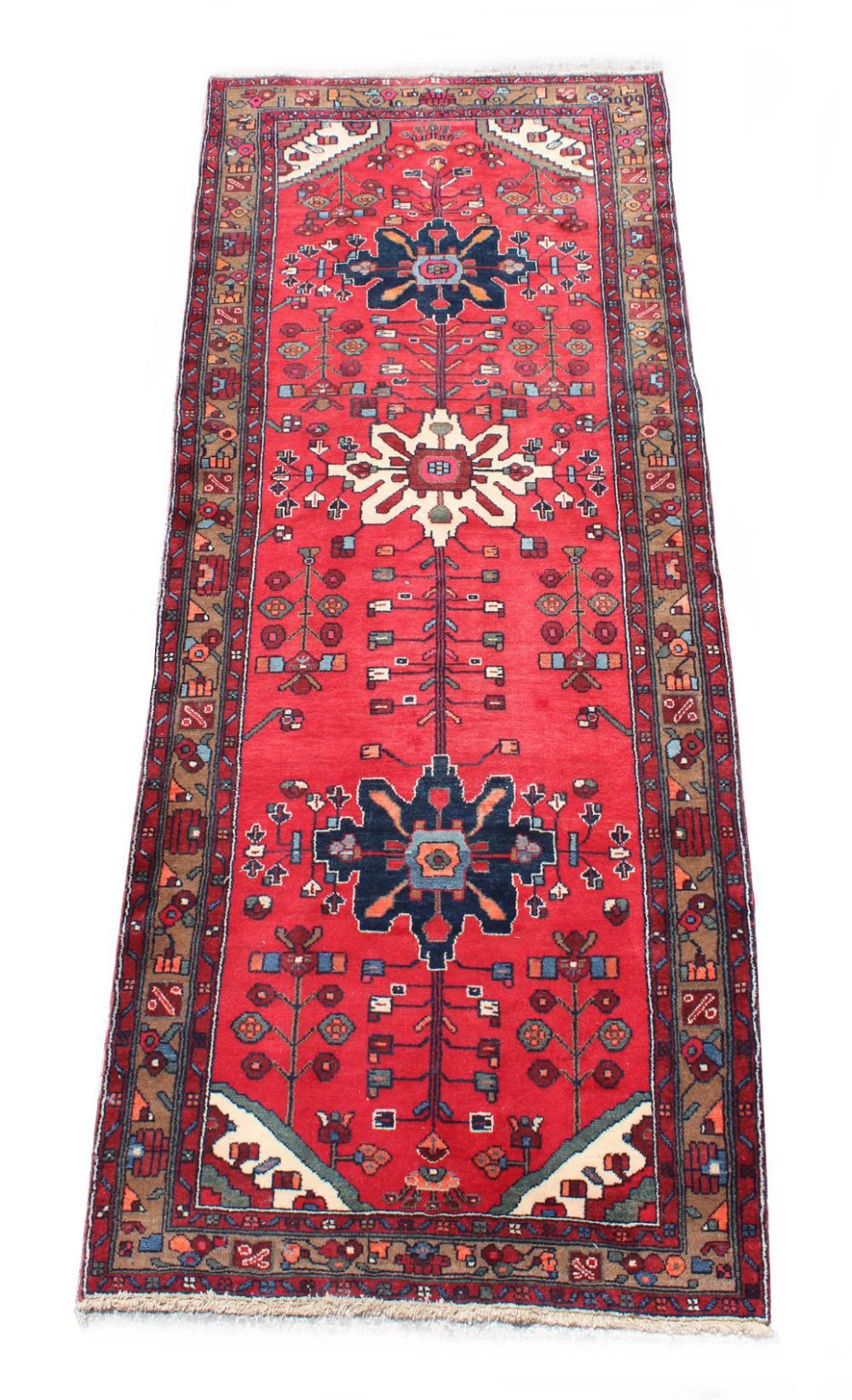 A Hamadan woollen hand-made carpet with red ground, 118 by 50ins. (300 by 125cms.).