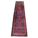An Esari woollen hand-made long rug with blue ground, 160 by 42ins. (405 by 107cms.).