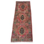 An Esari woollen hand-made long rug with beige ground, 115 by 44ins. (290 by 110cms.).
