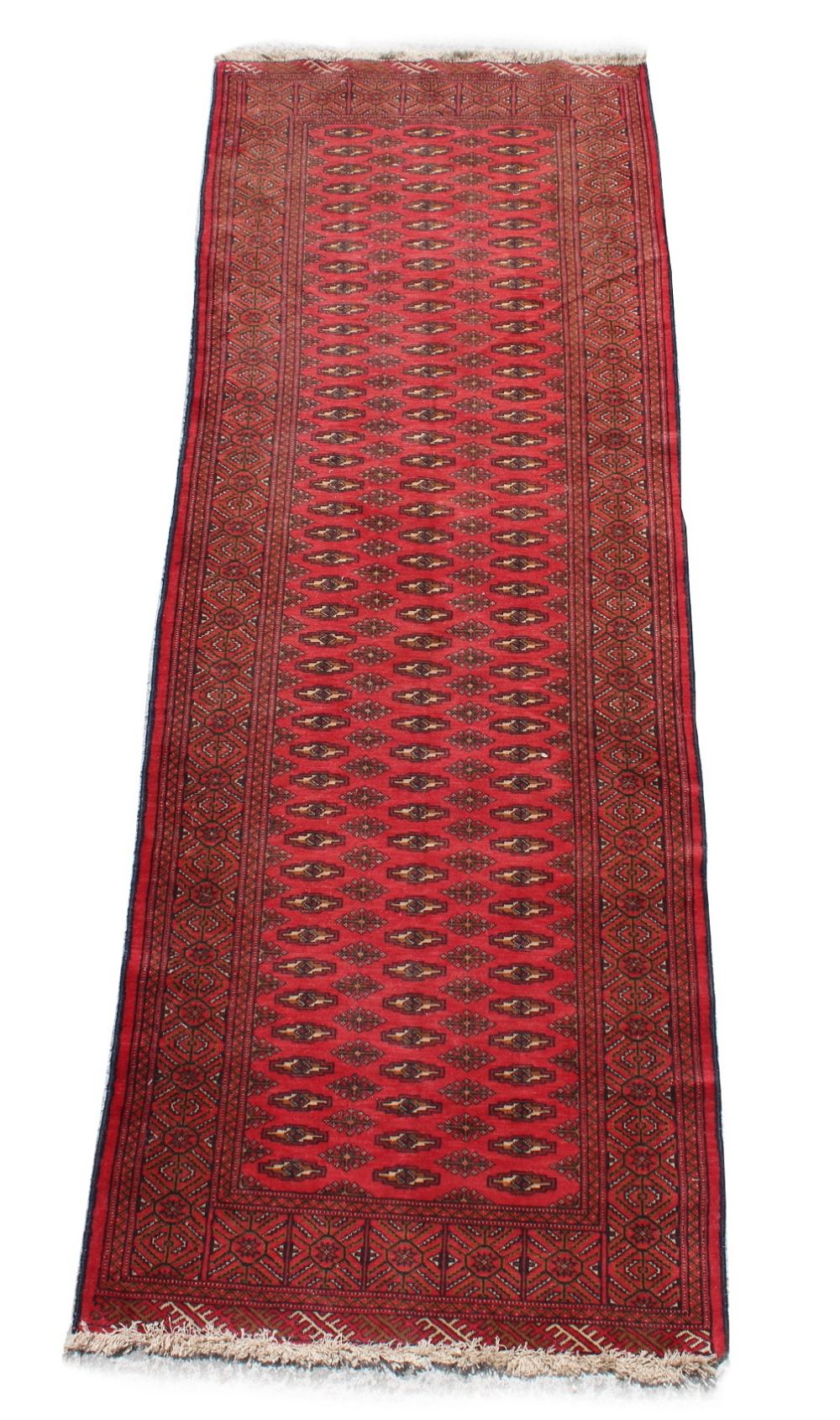 A Turkoman woollen hand-made long rug with red ground, 115 by 46ins. (290 by 103cms.).