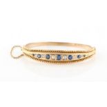 A late Victorian unmarked yellow gold sapphire & diamond hinged bangle, the seven oval cut sapphires