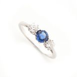 A sapphire & diamond three stone ring, the round cut sapphire weighing approximately 0.59 carat,