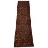 A Belouch woollen hand-made runner with copper ground, 116 by 28ins. (295 by 71cms.).