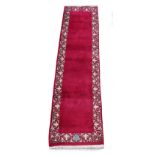 A Tabriz woollen hand-made runner with burgundy ground, 124 by 32ins. (315 by 80cms.).