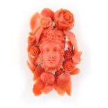A large late 19th / early 20th century carved coral brooch in the form of a mask within a border