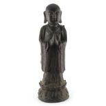 A Chinese bronze figure of Buddha, Ming Dynasty (1368-1644), modelled standing in prayer, on