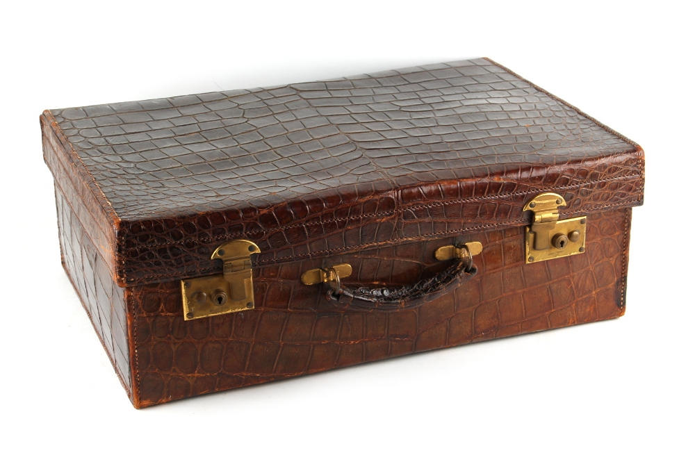 Property of a deceased estate - an early 20th century crocodile skin suitcase, with brass double