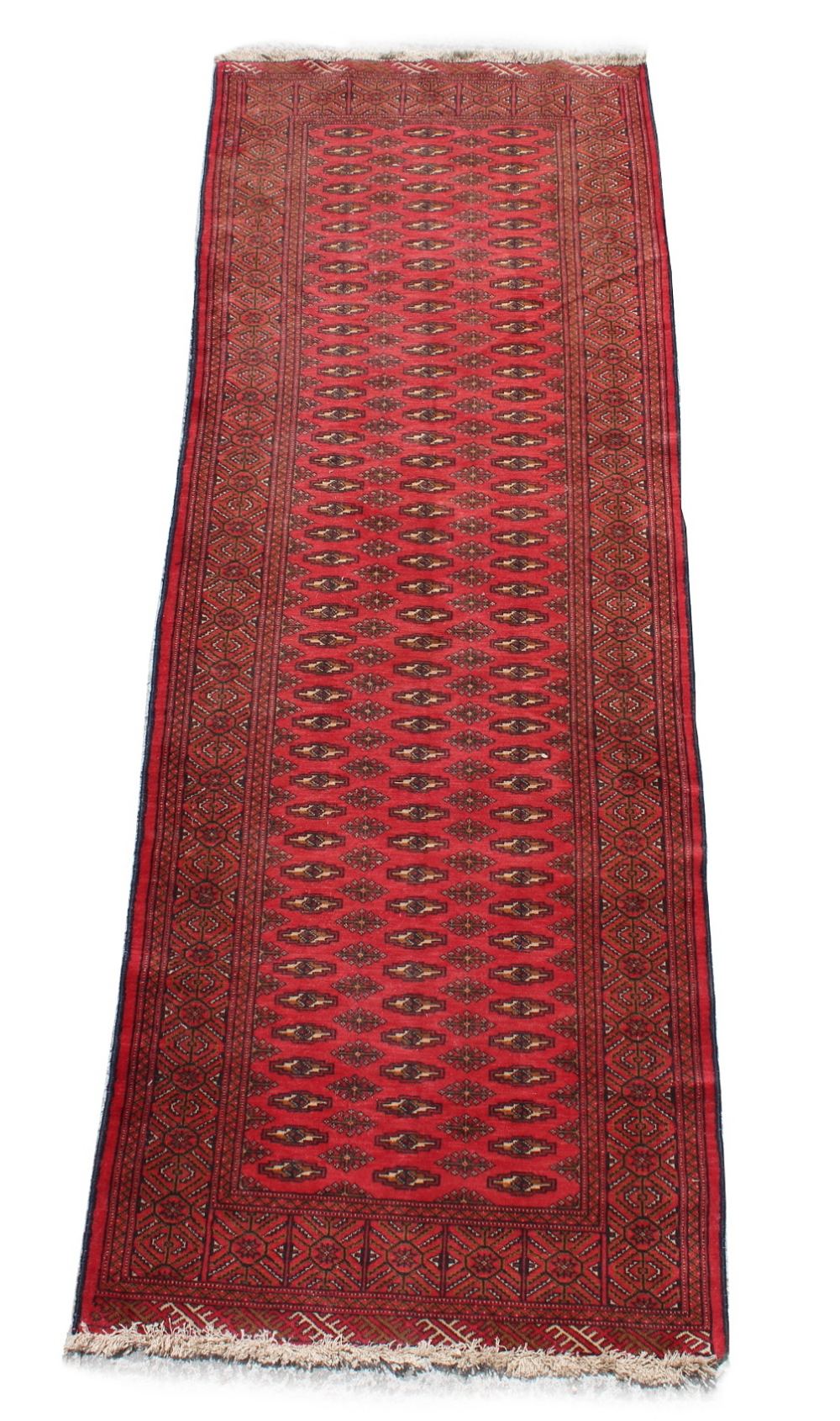 A Turkoman woollen hand-made carpet with red ground, 115 by 46ins. (290 by 103cms.).