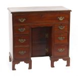 Property of a gentleman - a mahogany kneehole desk with seven drawers flanking a central recessed