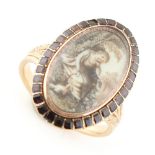 An unmarked Georgian yellow gold ring with oval panel painted in sepia with a girl & dog sitting