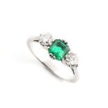 An unmarked white gold emerald & diamond three stone ring, the octagonal cut emerald weighing