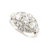 An Art Deco style unmarked white gold diamond cluster ring, with a row of three round brilliant