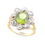 An unmarked yellow gold peridot & diamond cluster ring, the oval cut peridot weighing