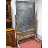 A School Blackboard, circa 1900, with swivel action, on oak trestle stand, 104.5cm wide.