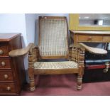 A XIX Century Teak Reclining Plantation Chair, with a caned back and seat, turned spindles, dish