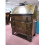 A 1930's Oak Bureau, with fall front, fitted interior, over three drawers in bracket feet.