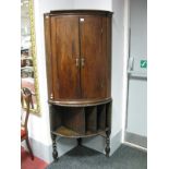 An Early XIX Century Oak Bow Fronted Corner Cupboard, together with an oak corner stand on barley