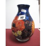 A Moorcroft Pottery Vase, painted with pansies poppies and other flowers on a blue ground,