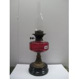 A XIX Century Oil Lamp, with a glass funnel, cranberry glass well, brass pedestal, black base.