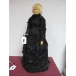 A Probable XIX Century Wax Headed Doll with Painted Features, wearing Victorian style mourning dress