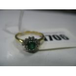 An 18ct Gold Emerald and Diamond Cluster Ring, claw set throughout, between tapered shoulders.