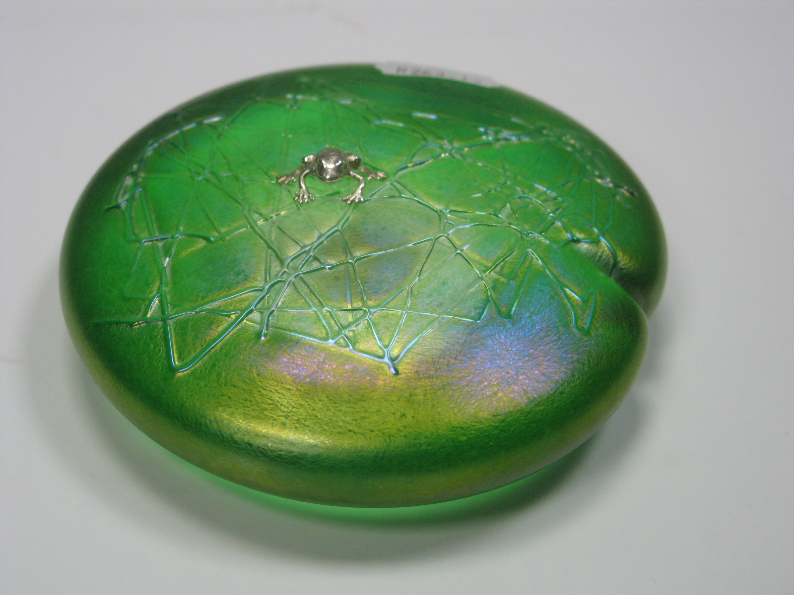 John Ditchfield Glasform; A green iridescent circular Lily Pad paperweight, mounted with a
