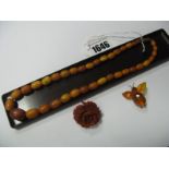 An Amber Coloured Single Strand Graduated Bead Necklace, a carved flowerhead brooch and an insect