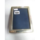 A Modern Hallmarked Silver Mounted Rectangular Photograph Frame, of plain design, on velvet easel