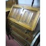 An Oak Bureau with Linen fold Fall Front, knulled top drawer over two others on squat block legs,