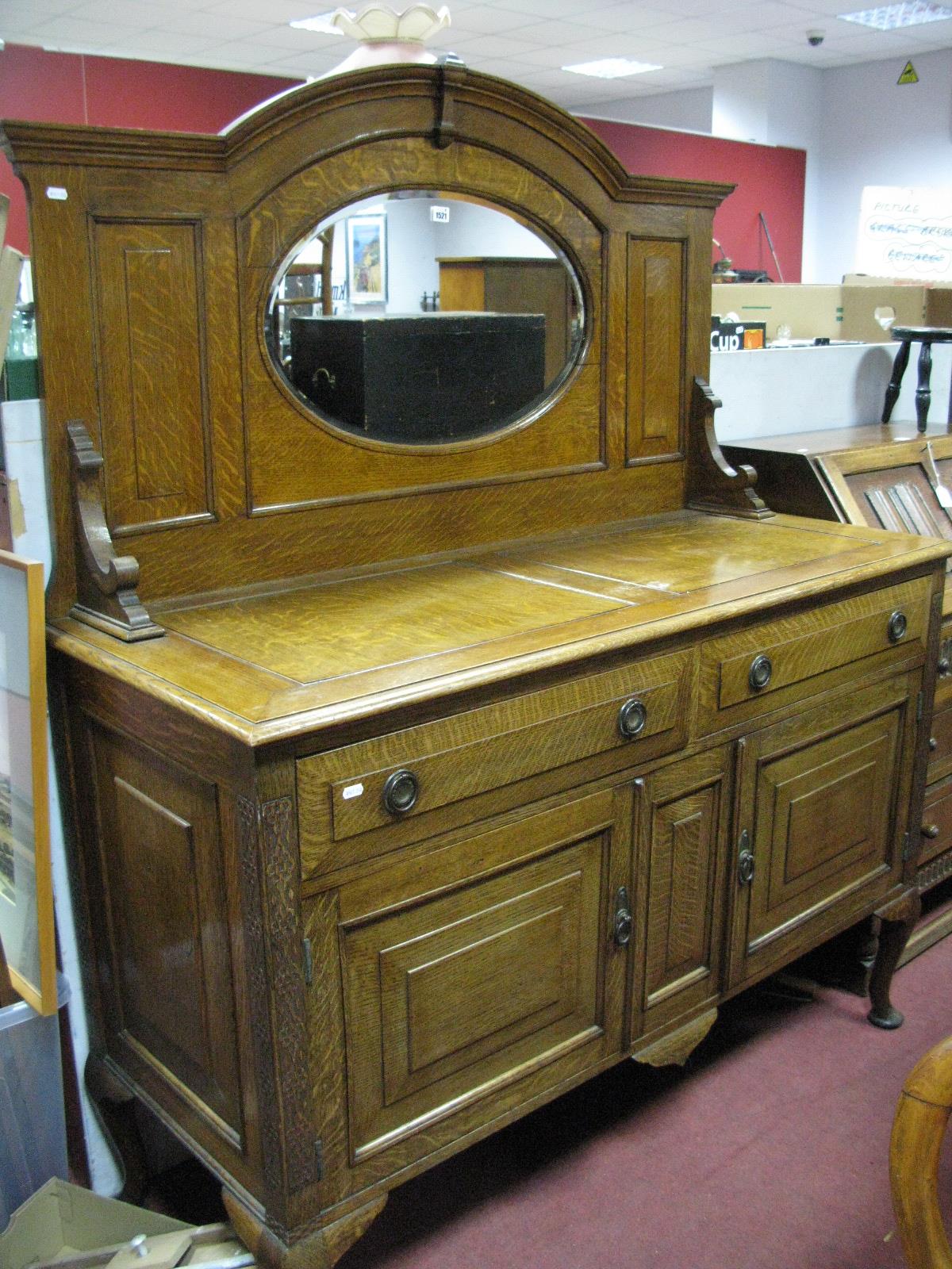 An Oak Mirror Back Sideboard, oval mirror below moulded arch, fitted with two frieze drawers over