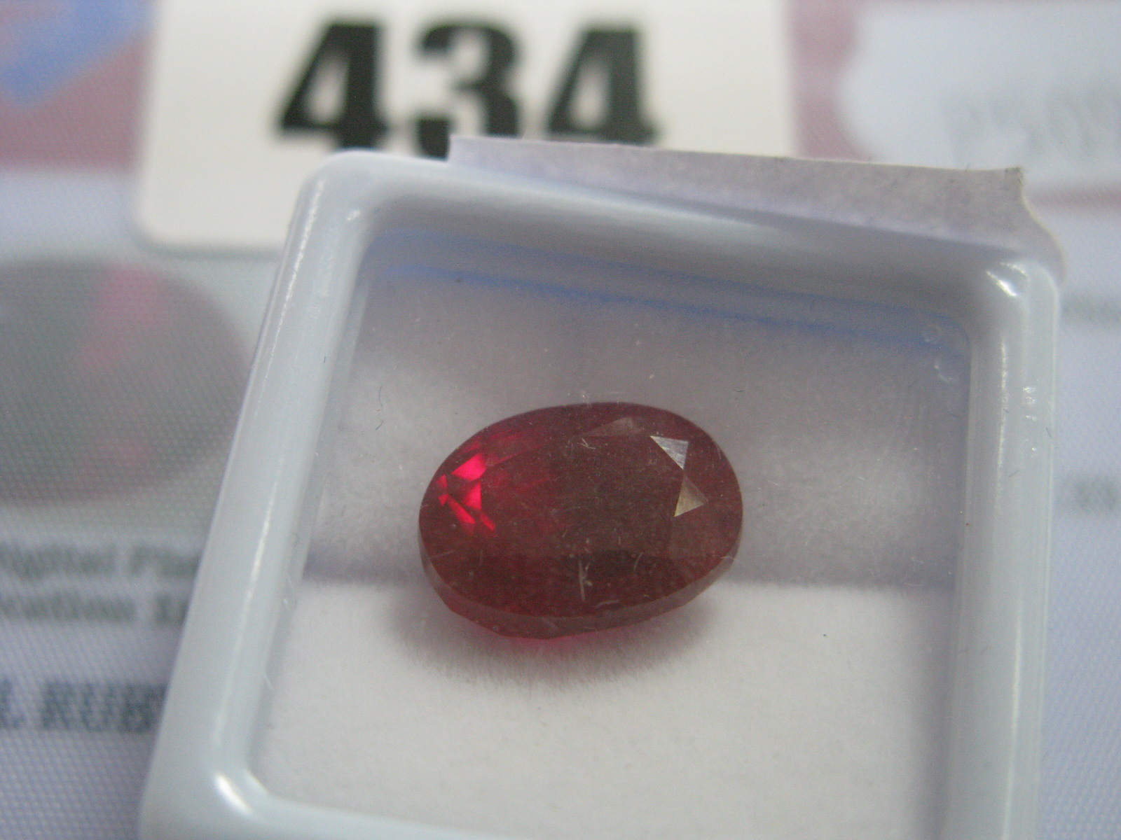 An Oval Cut Ruby, unmounted, with a Global Gems Lab Certificate card stating carat weight 7.95 (