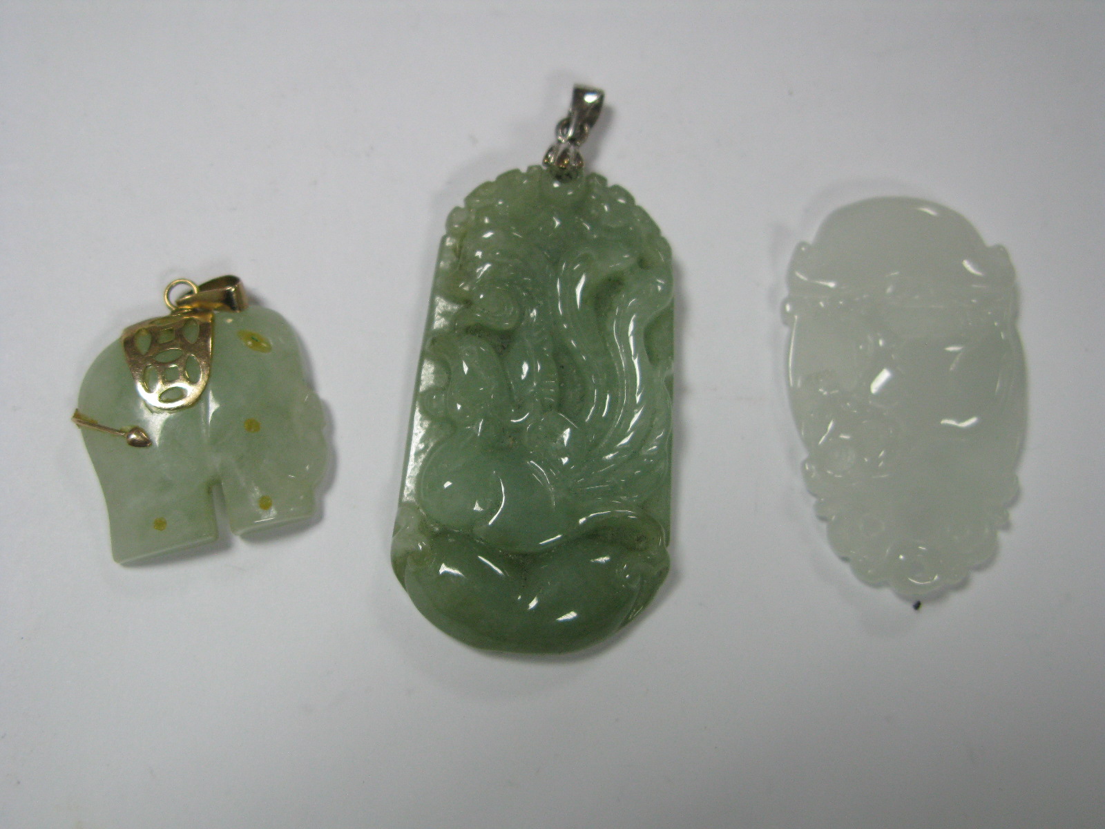 A Carved Oriental Jadeite Pendant, another similar of elephant design and one other. (3)