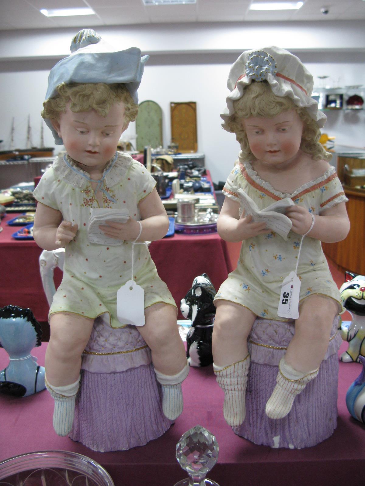 A XIX Century Pair of Continental Bisque Figures, of a seated boy and girl, reading books. (