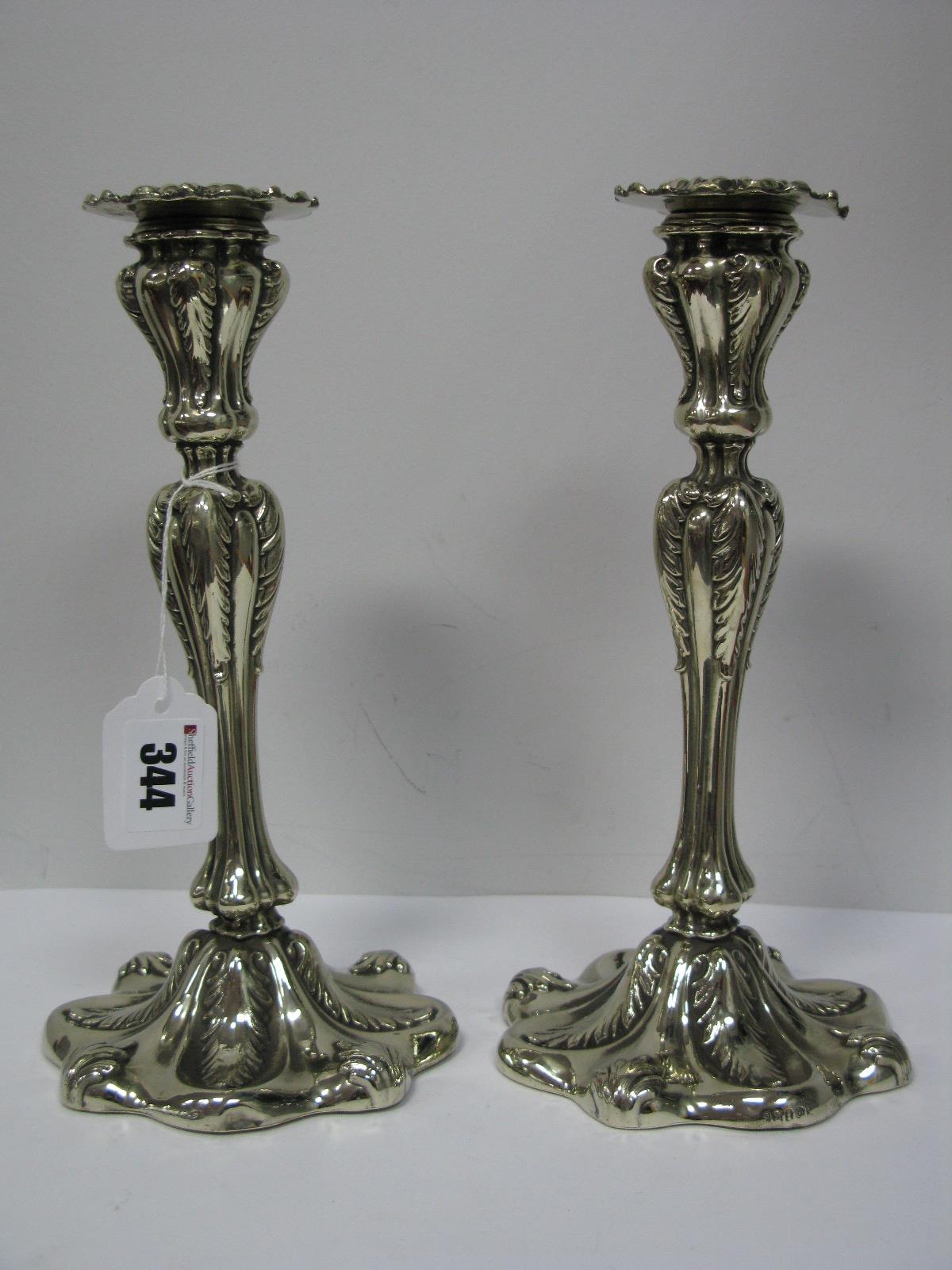 A Pair of Decorative Continental Style Plated Candlesticks, each shaped base with stylised leaf