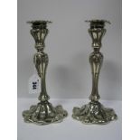 A Pair of Decorative Continental Style Plated Candlesticks, each shaped base with stylised leaf