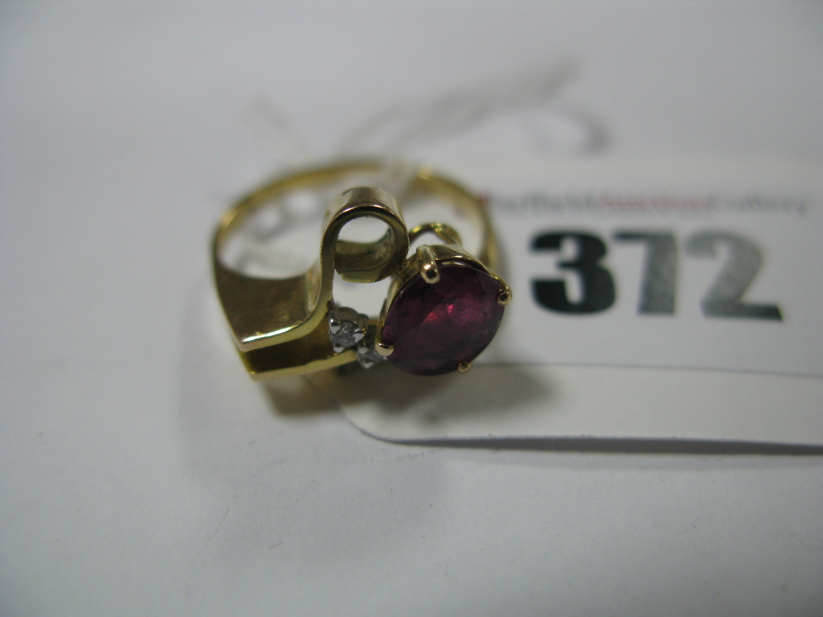 A Ruby and Diamond Set Cocktail Dress Ring, of abstract design, oval four claw set within stylised
