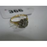 An 18ct Gold Cluster Dress Ring, illusion set highlights, between textured shoulders.