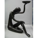 A Cast Bronzed Stylized Figure of a Nude, sitting cross legged holding a bowl.