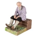 A RUSSIAN PORCELAIN FIGURE OF AN OLD MAN ON A IZBA BENCH, GARDNER PORCELAIN FACTORY, LATE 19TH C