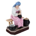 A RUSSIAN PORCELAIN FIGURE OF A PEASANT WOMAN COOKING, GARDNER PORCELAIN FACTORY, LATE 19TH C