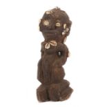 Kniende FigurHolz geschwärzt, bestückt mit Kaurimuscheln, H: 36 cm.- - -25.00 % buyer's premium on